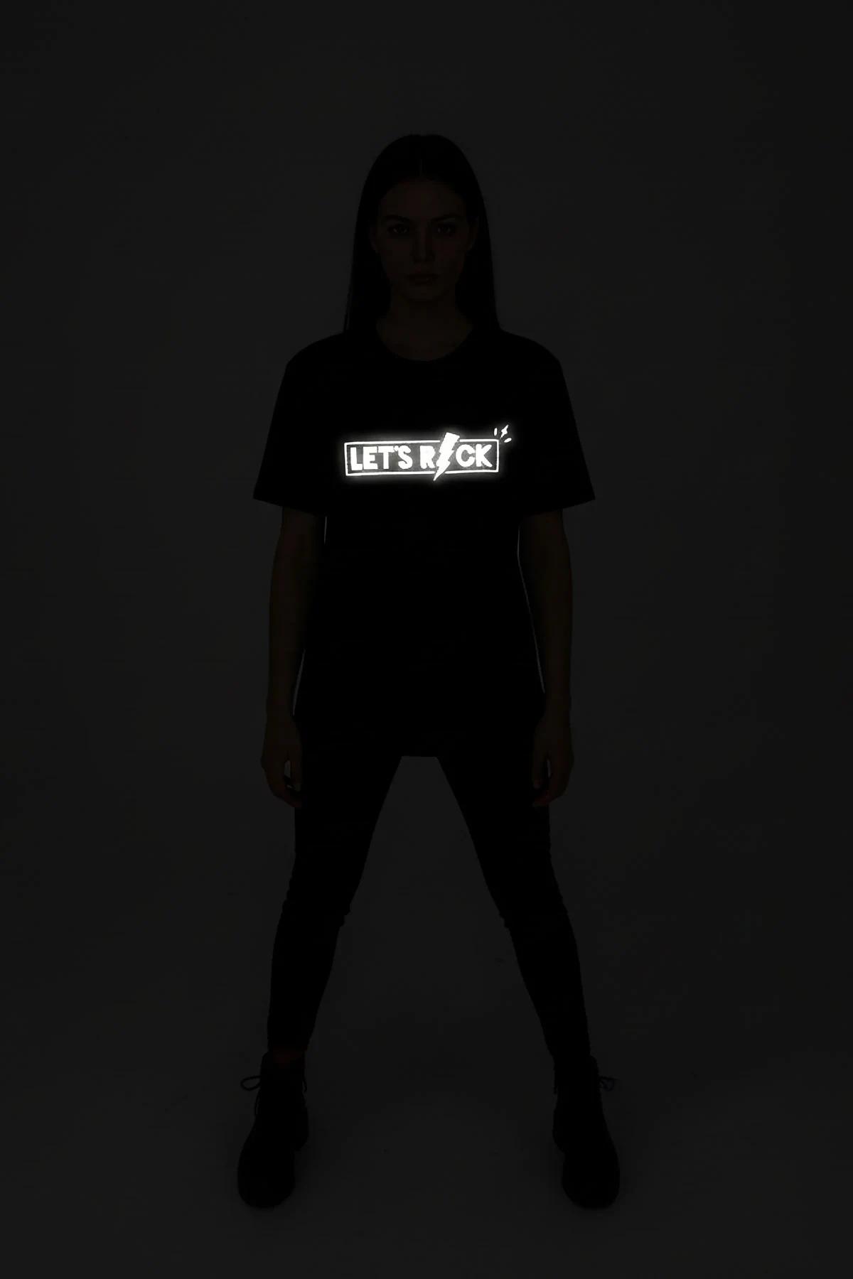 LET'S ROCK reflektör baskılı siyah tişört model üzerinde tam boy görünüm, oturur pozisyon