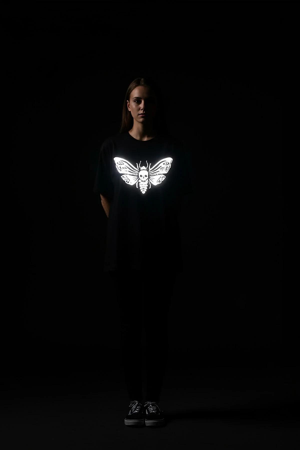 Black cotton blend t-shirt with a striking white reflective skull moth graphic on the chest.