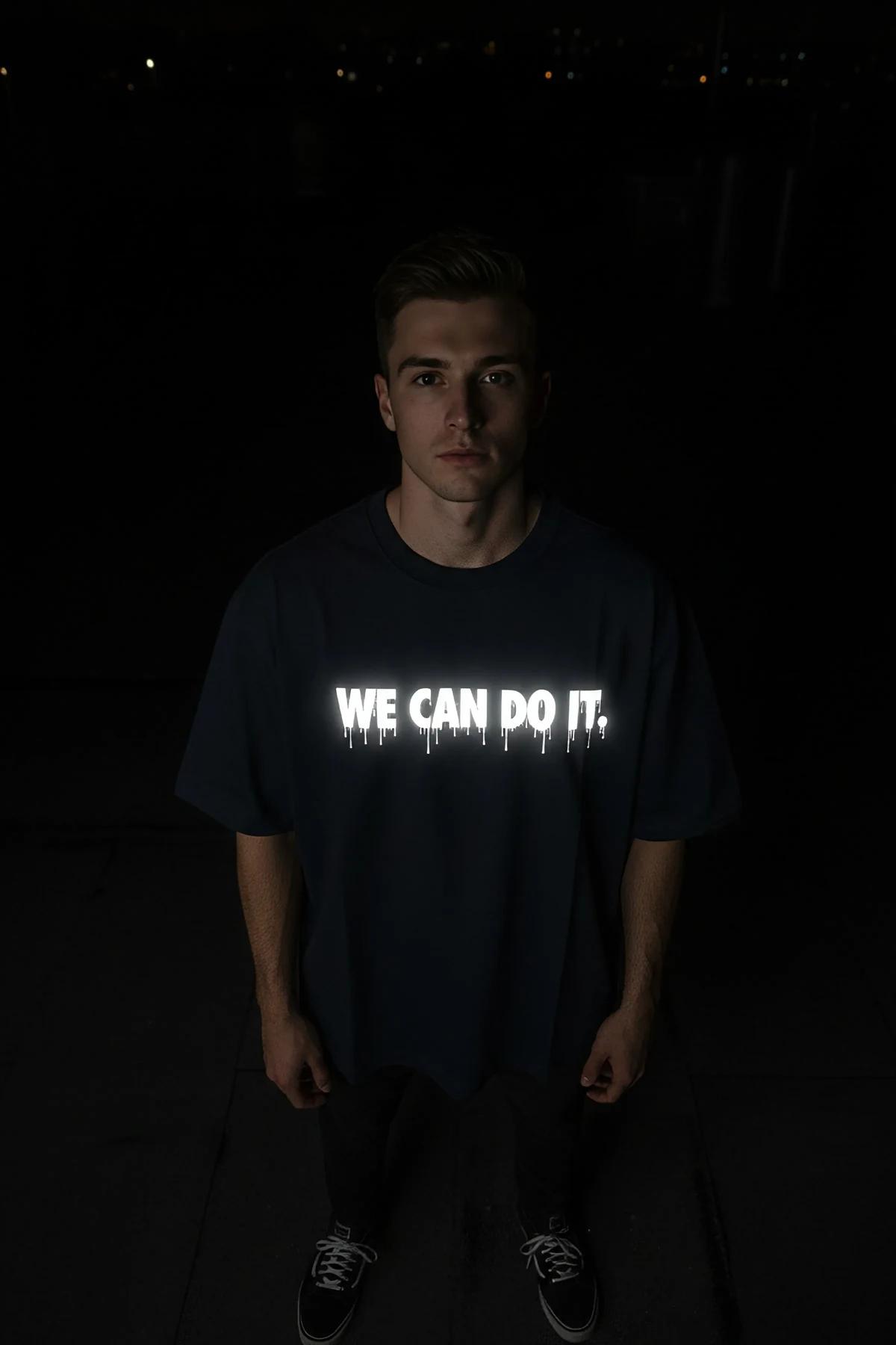 Siyah oversize tişört WE CAN DO IT reflektör baskı, gece sokak ortamında model üzerinde