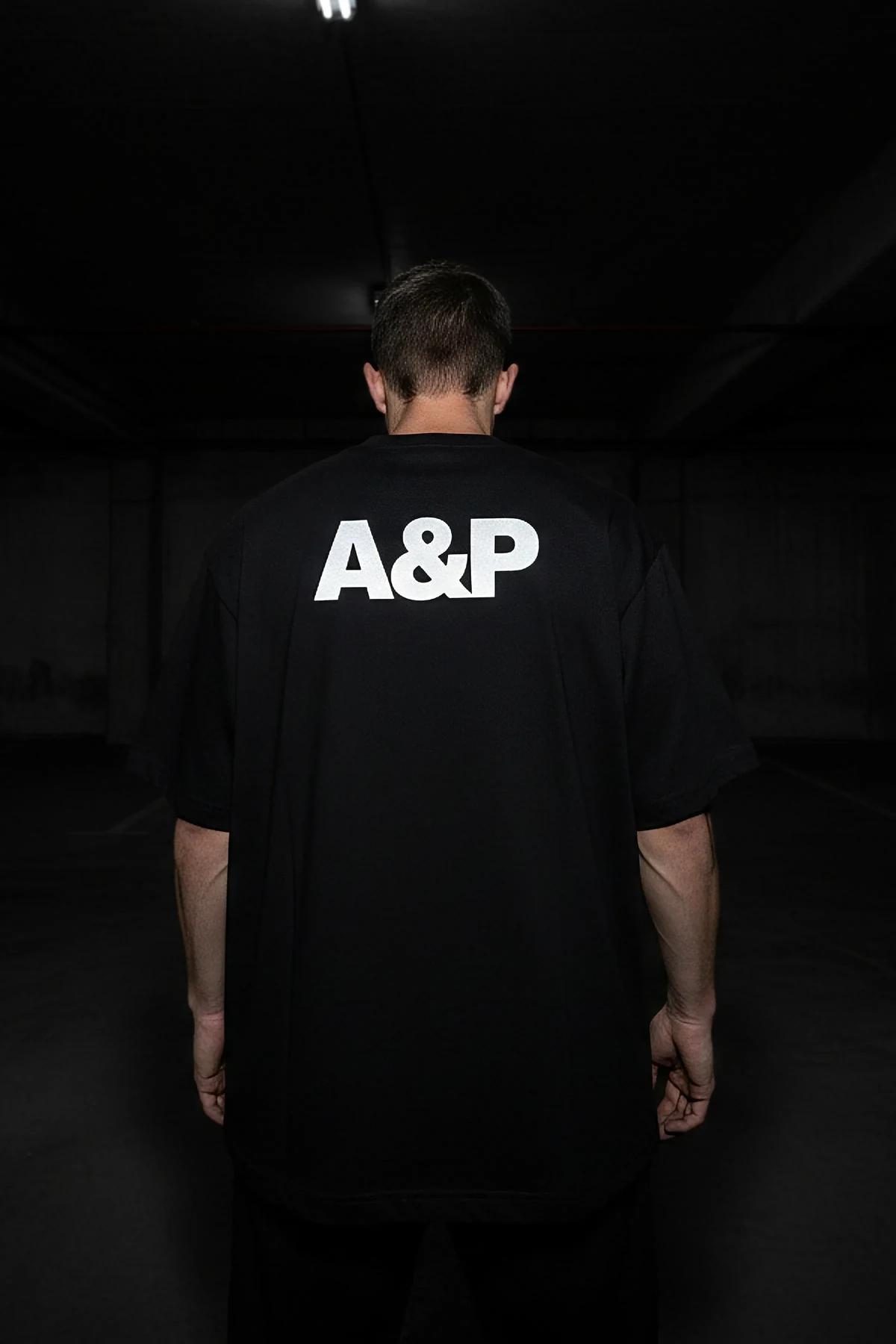 A&P reflektörlü siyah oversize tişört önden görünüm, sol göğüste küçük A&P baskısı