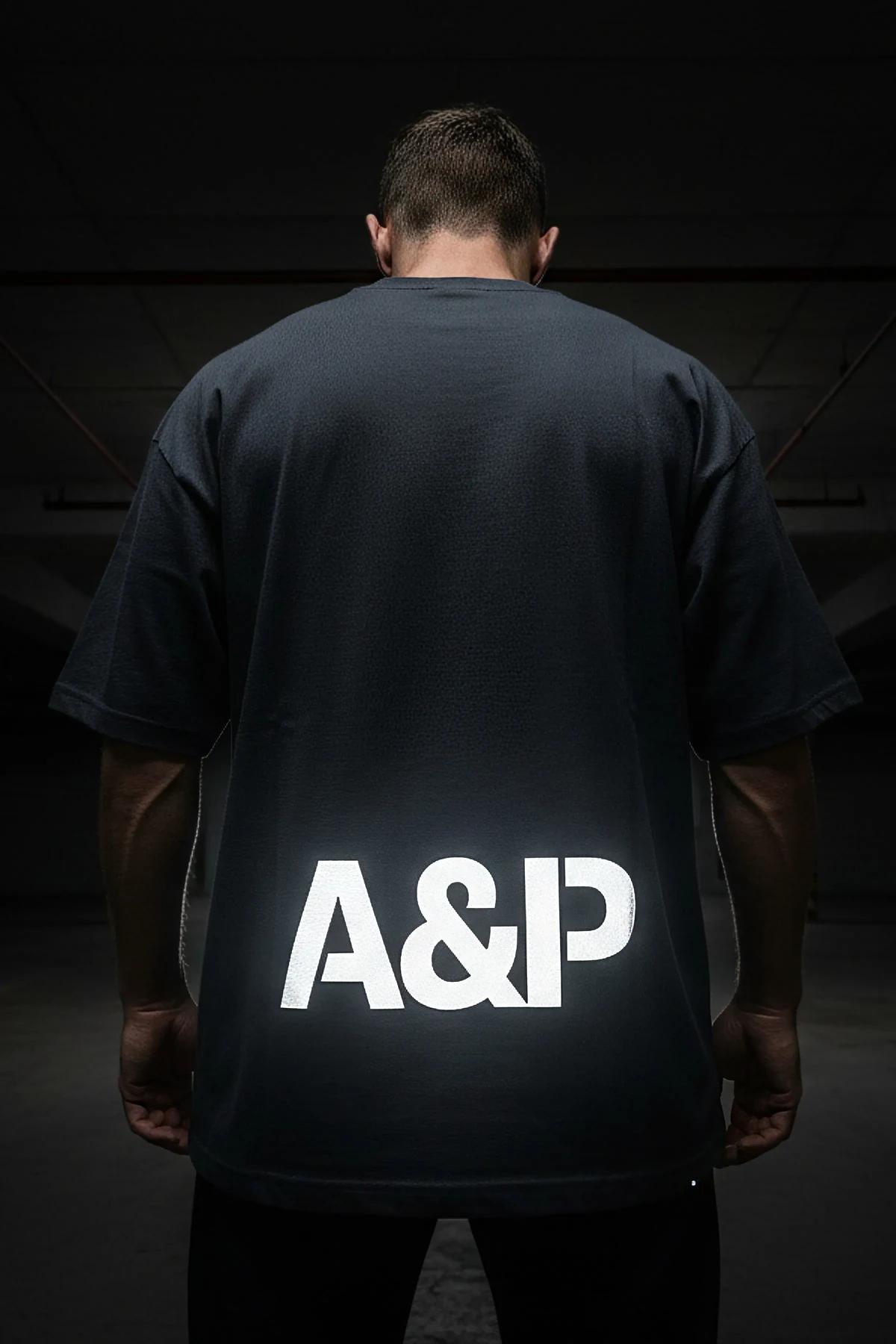 A&P reflektörlü tişört sol kol detayı, dikey A&P baskısı reflektör parlamasıyla