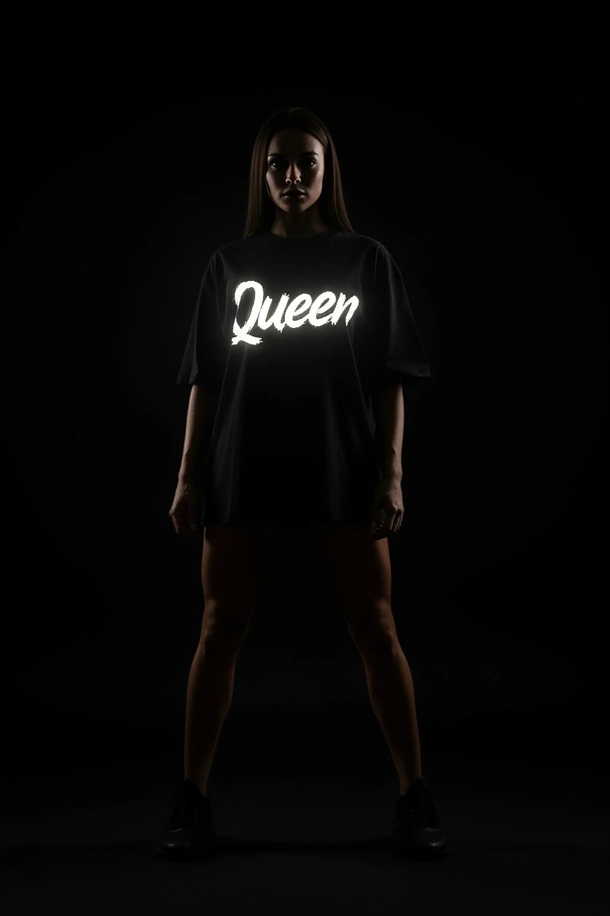 Queen reflektörlü ön baskılı siyah oversize tişört, kadın model güneş gözlüğüyle poz veriyor