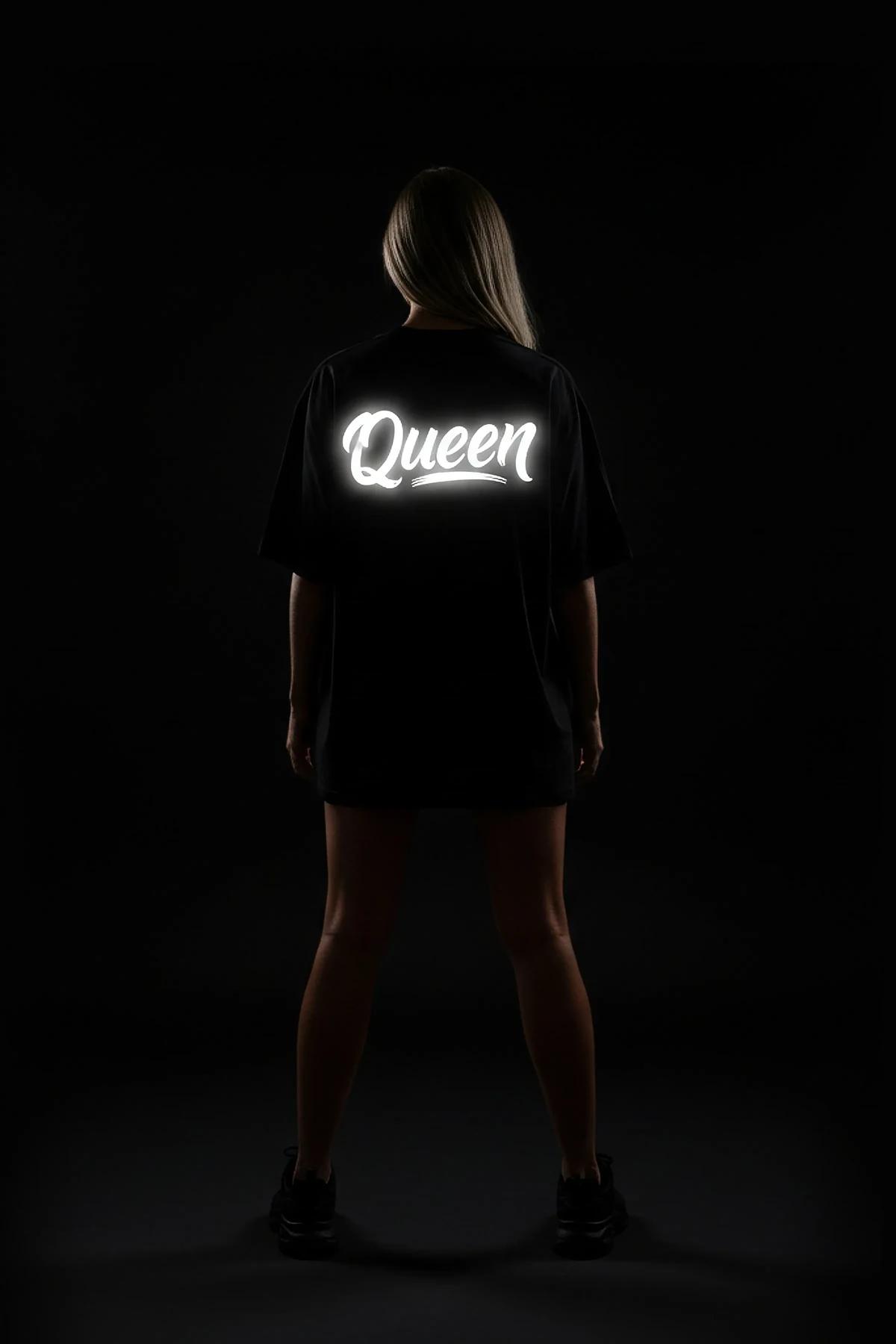 Queen reflektörlü ön baskılı siyah oversize tişört, kadın model güneş gözlüğüyle poz veriyor