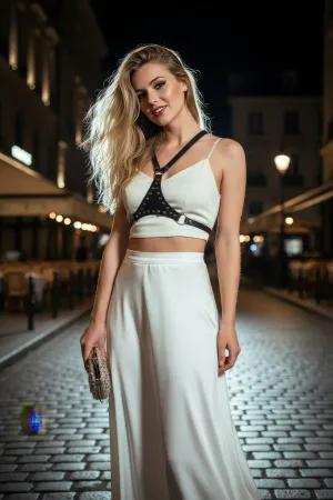 Siyah çivili vegan deri kadın omuz ve göğüs aksesuarı, beyaz crop top ile kombinlenmiş.