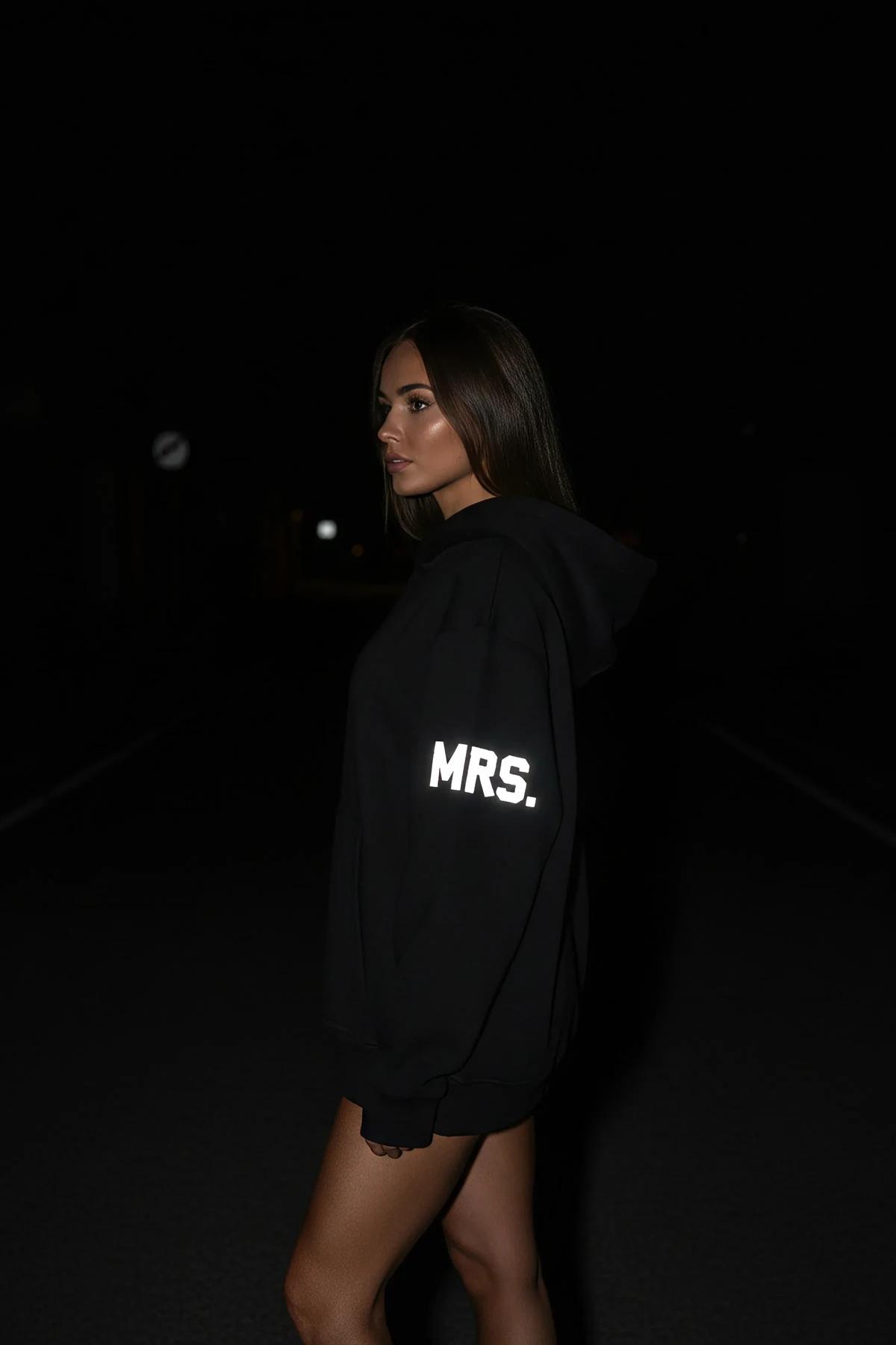 MRS. reflektörlü sırt baskılı siyah oversize kapüşonlu sweatshirt, kadın üzerinde gece flaş ışığında parlıyor