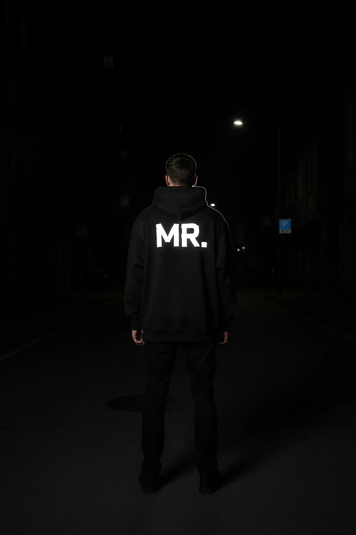 MRS. reflektörlü sırt baskılı siyah oversize kapüşonlu sweatshirt, kadın üzerinde gece flaş ışığında parlıyor