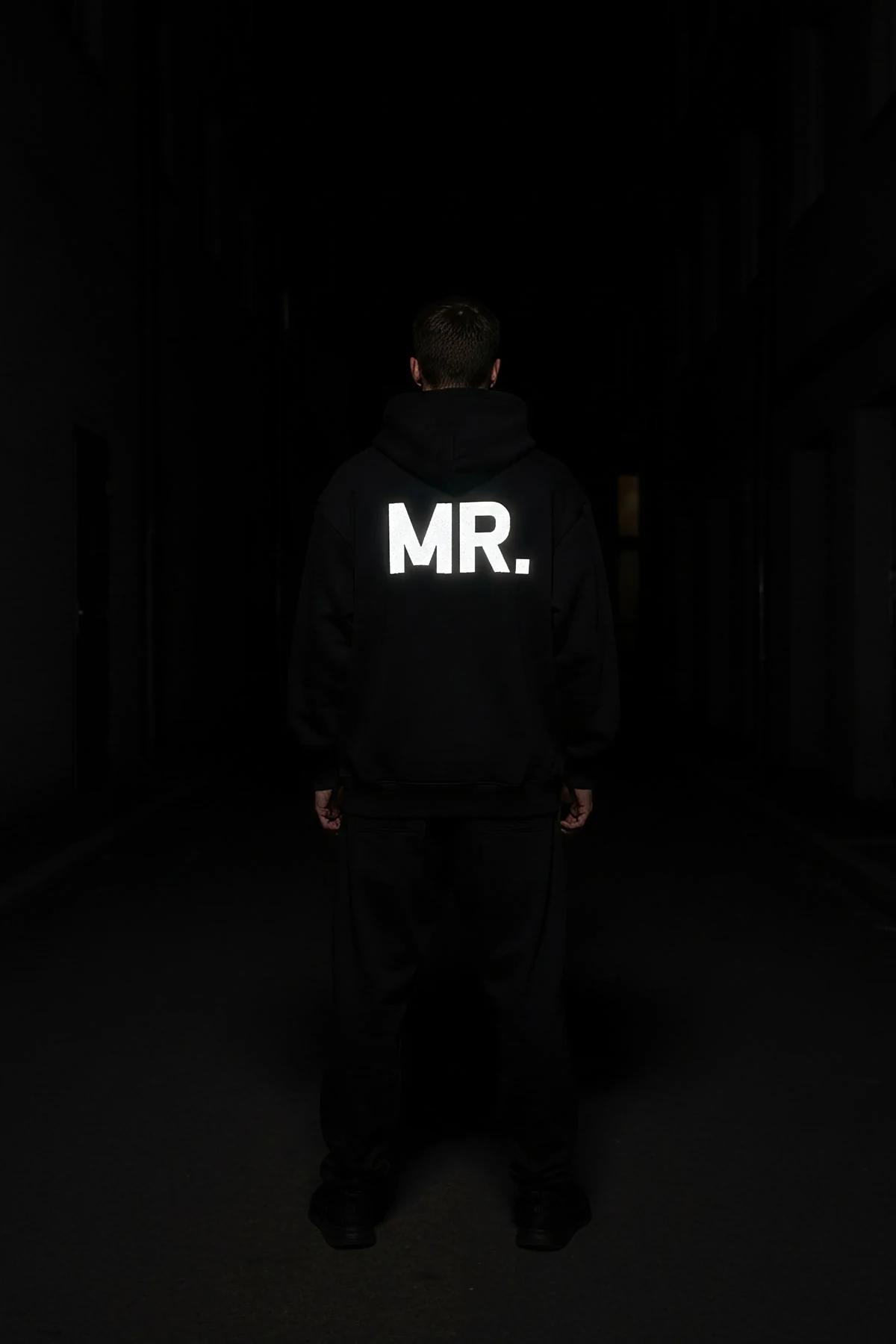 MRS. reflektörlü sırt baskılı siyah oversize kapüşonlu sweatshirt, kadın üzerinde gece flaş ışığında parlıyor