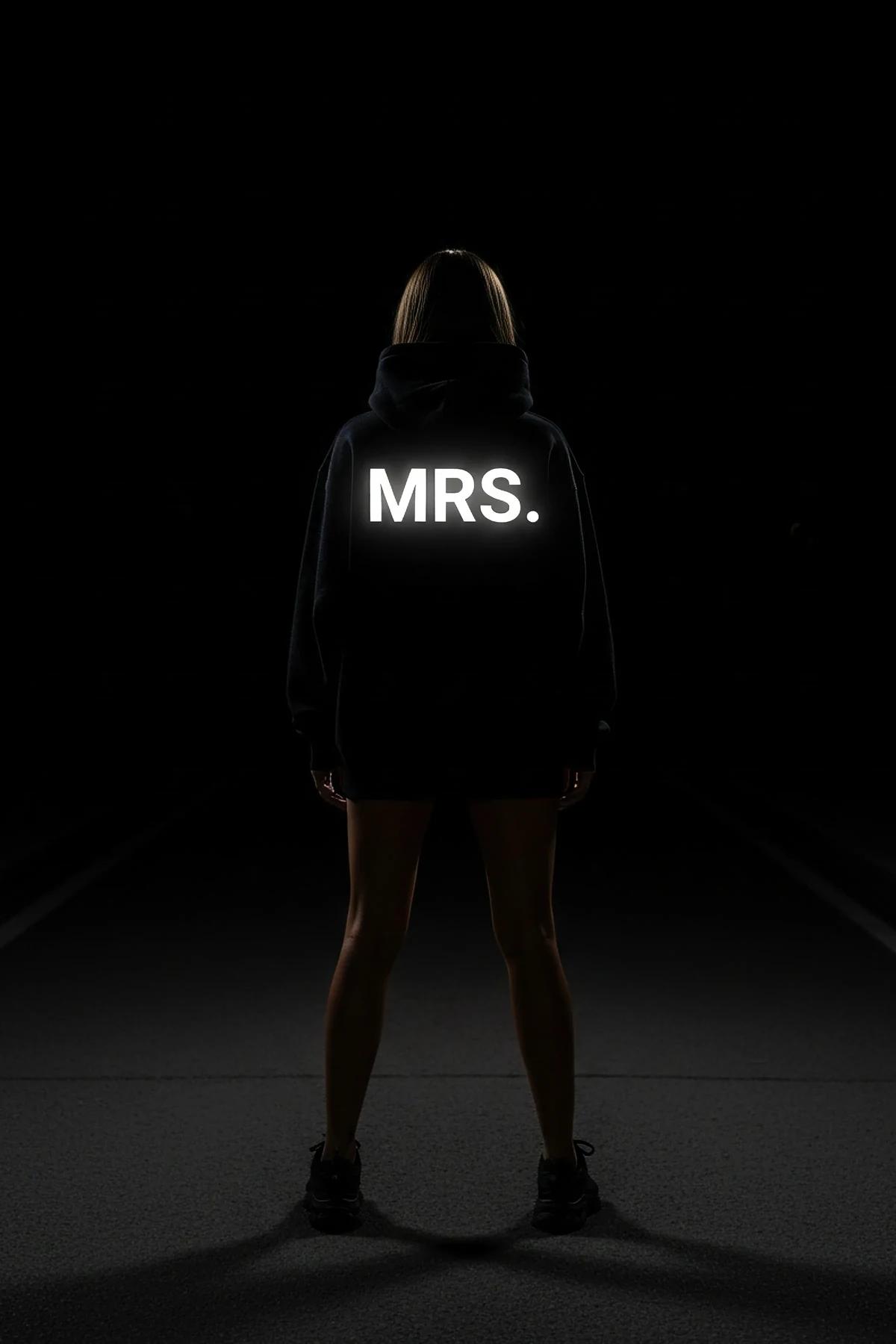 MRS. reflektörlü sırt baskılı siyah oversize kapüşonlu sweatshirt, kadın üzerinde gece flaş ışığında parlıyor