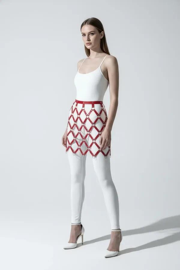 red faux leather diamond grid mini skirt overlay harness with silver O-rings at each strap intersection worn over white leggi