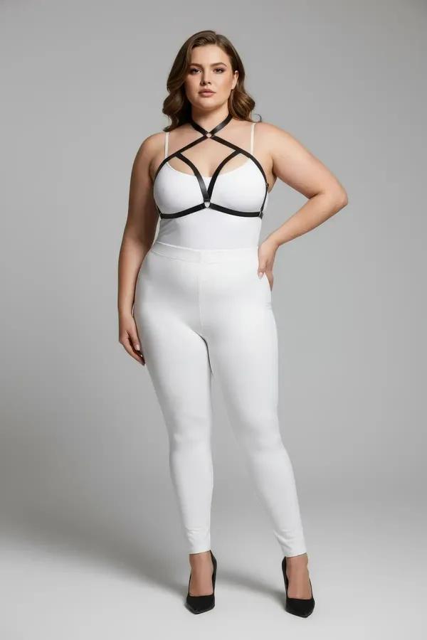 black faux leather strappy chest harness with silver O-ring geometric X-strap cage worn over white bodysuit plus size model