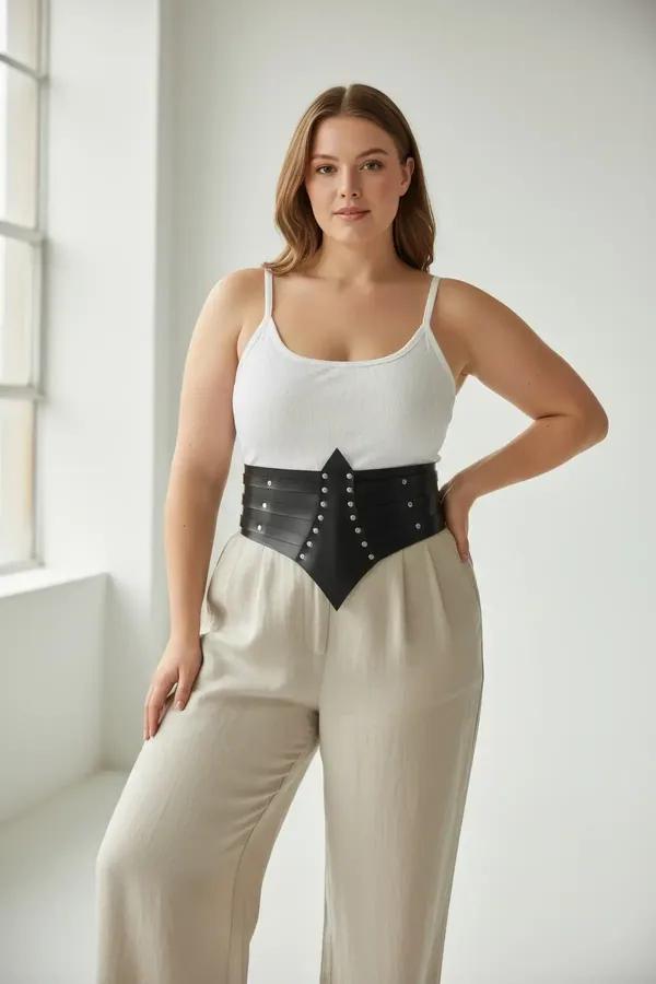 black faux leather waist cincher belt with silver dome studs and pointed chevron front panel worn over cream camisole