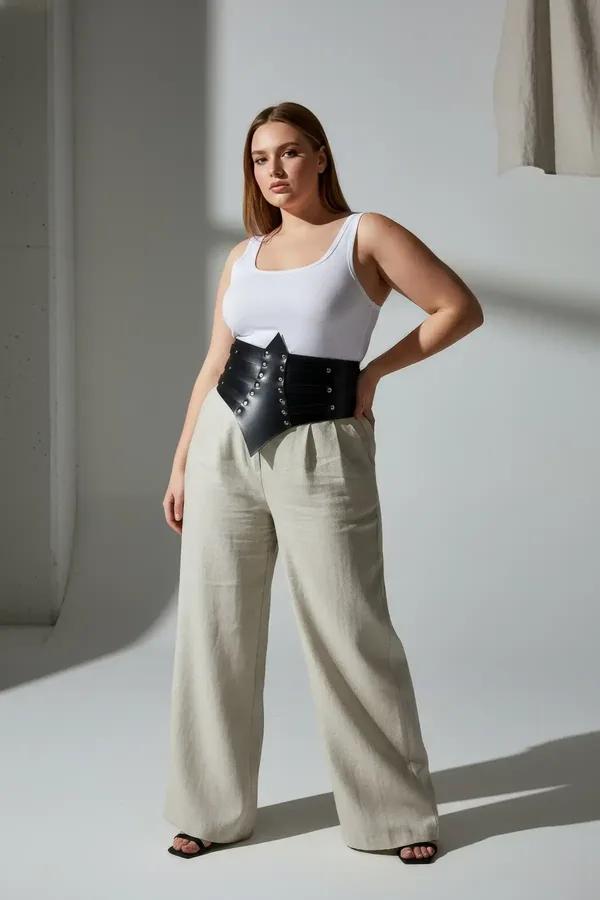 black faux leather waist cincher belt with silver dome studs and pointed chevron front panel worn over cream camisole