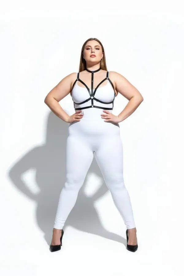 black faux leather strappy chest harness with collar neck strap and central silver O-ring worn over white bodysuit
