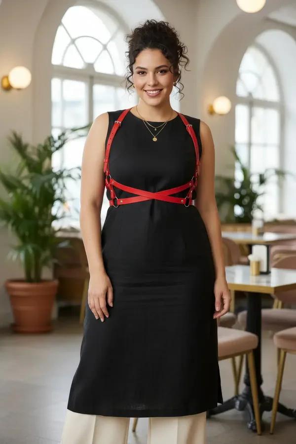 red faux leather chest harness with gold O-rings and X-cross strap pattern worn over black dress