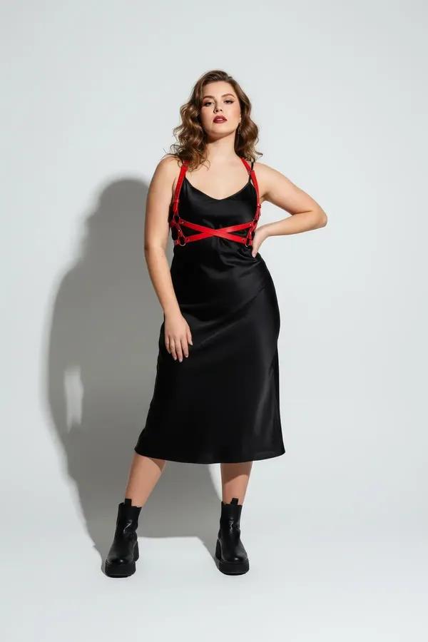 red faux leather chest harness with gold O-rings and X-cross strap pattern worn over black dress