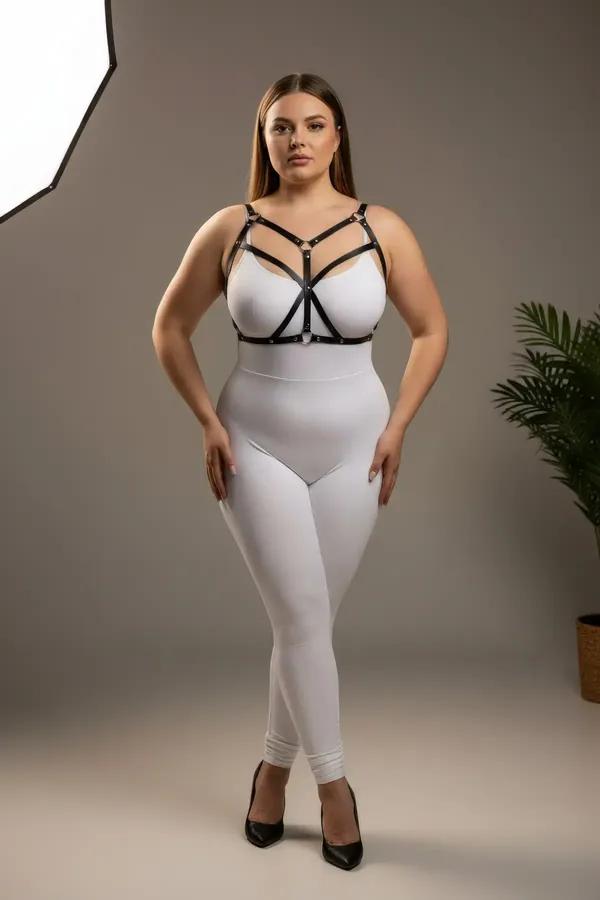 black strappy faux leather body harness with silver O-ring detail worn over white bodysuit plus size model