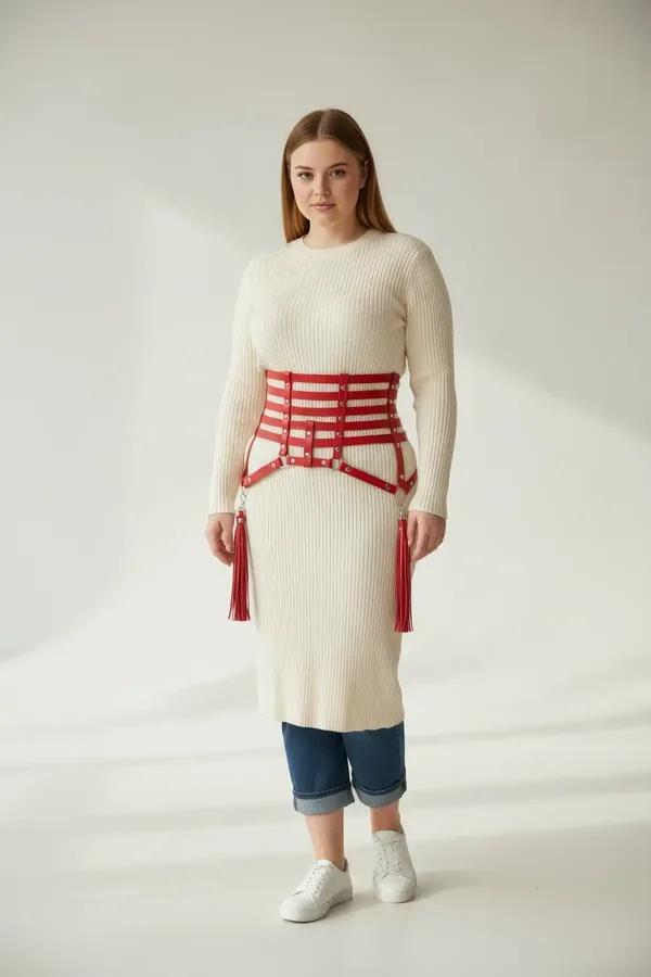 red faux leather caged waist harness with silver O-ring hardware and fringe tassels worn over grey dress