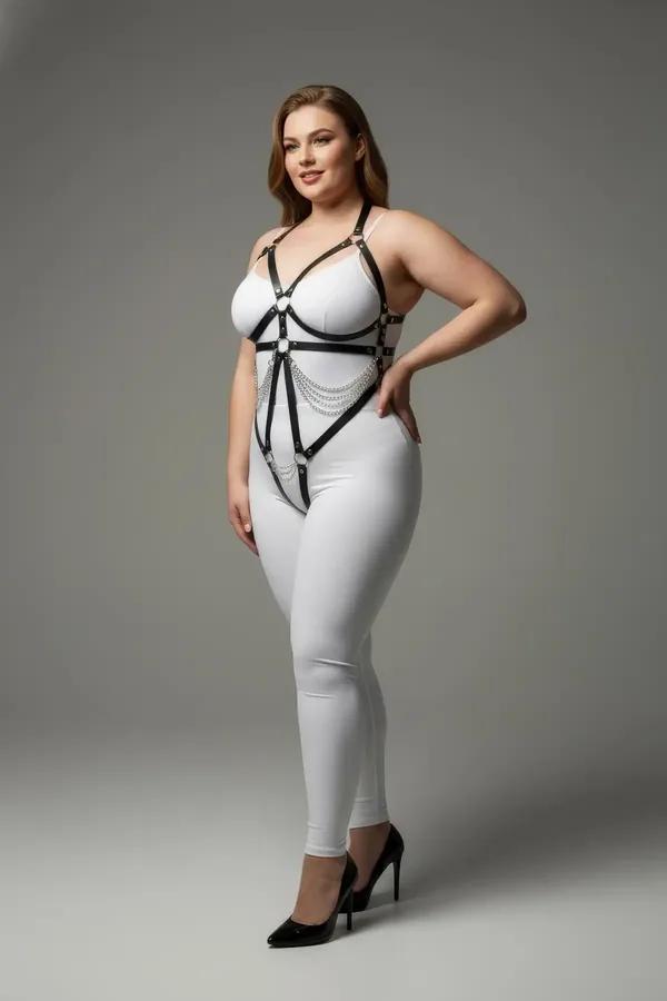 black faux leather strappy underbust harness with silver draped chains and O-ring closure worn over white bodysuit