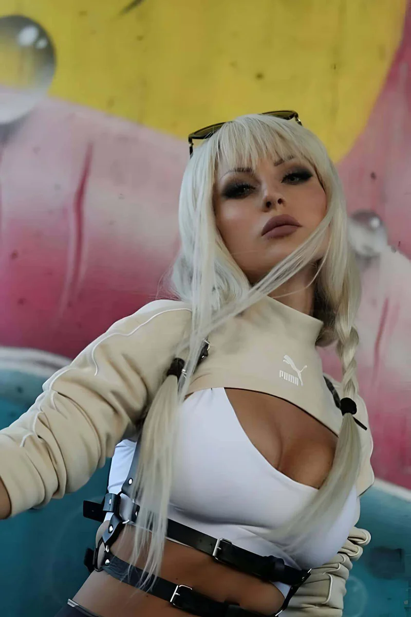Model wearing black faux leather body harness over a white top, front view