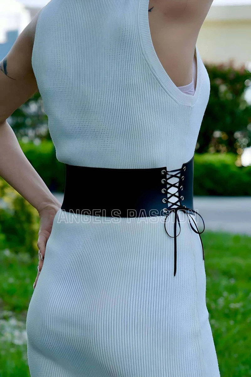 Black lace-up faux leather corset belt cinches white ribbed dress from side