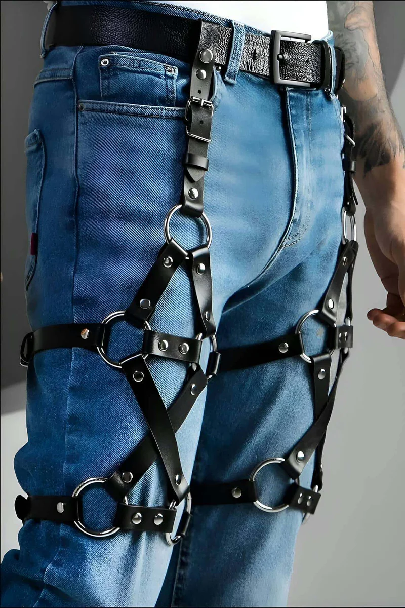 Close-up of silver metal rings on black faux leather leg harness.