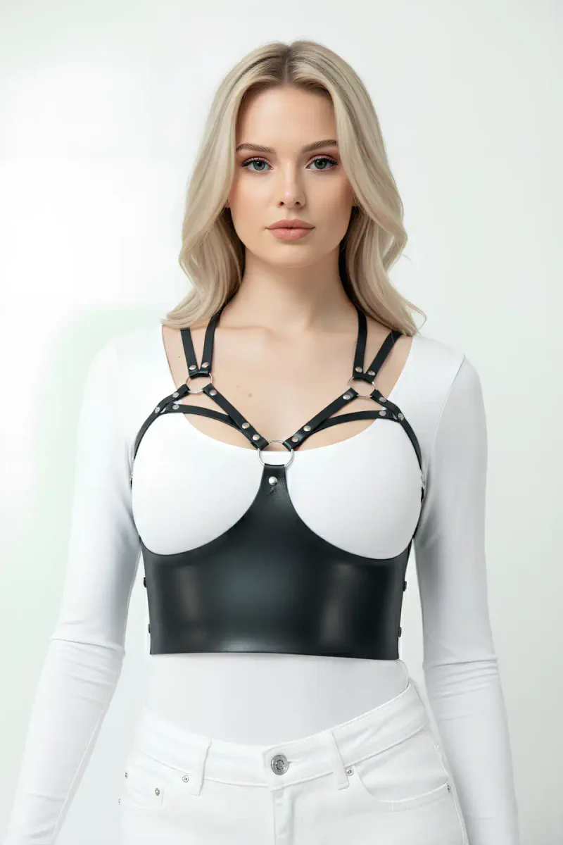 Siyah deri harness büstiyer, metal halkalar ve düğmelerle bezeli, üzerine beyaz tişört giyilmiş hali