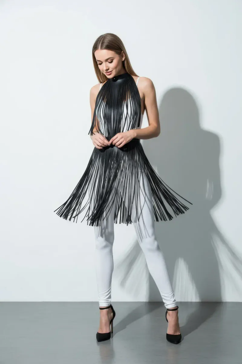 Model wearing black faux leather fringe mock neck overlay over white top and leggings