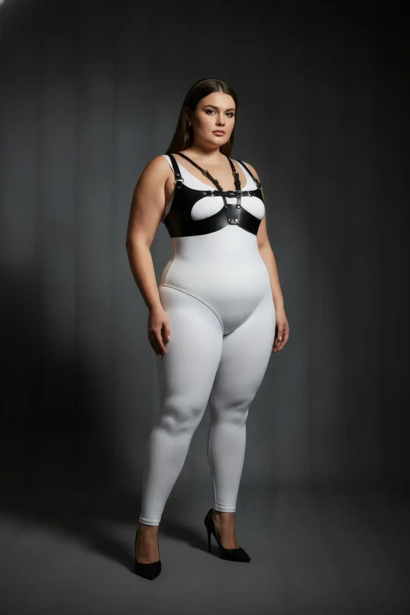 Model wearing black faux leather harness bra layered over white clothing with O-ring detail